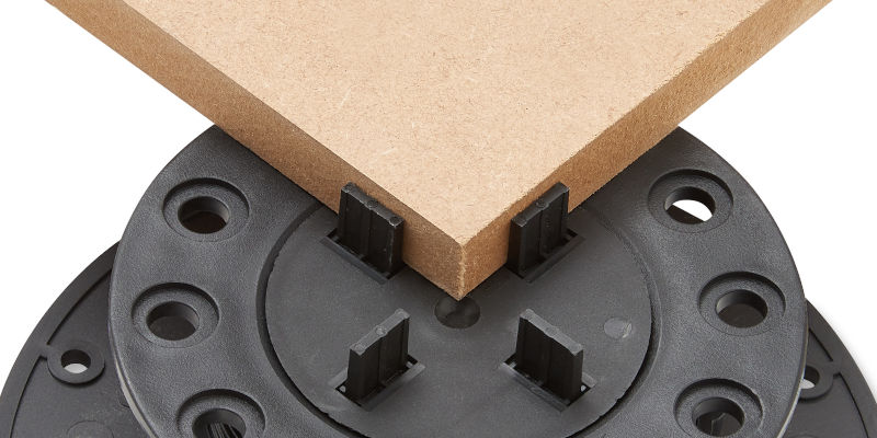 The corner of a paving slab sitting on an adjustable plastic pedestal