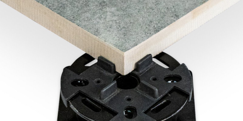 The corner of a paving slab sitting on an adjustable metal pedestal