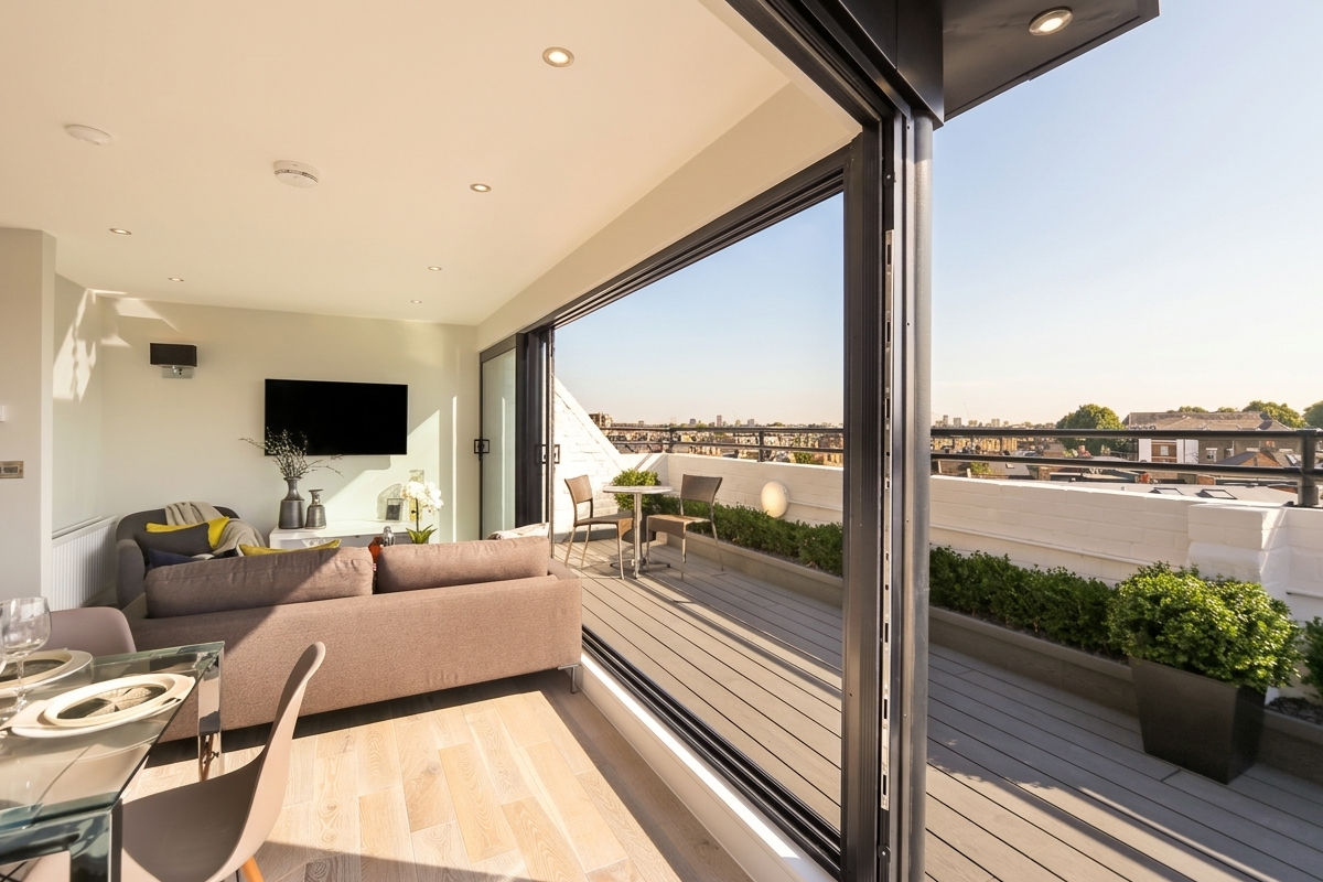 Bright living room with open sliding doors leading to balcony with chairs and plants