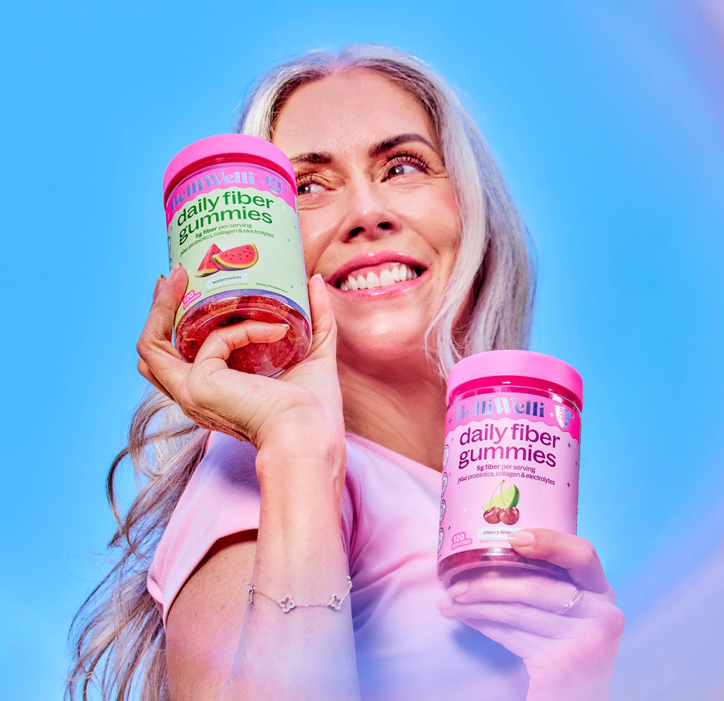 Woman smiling and holding Cherry Limeade and Watermelon BelliWelli fiber gummy jars
