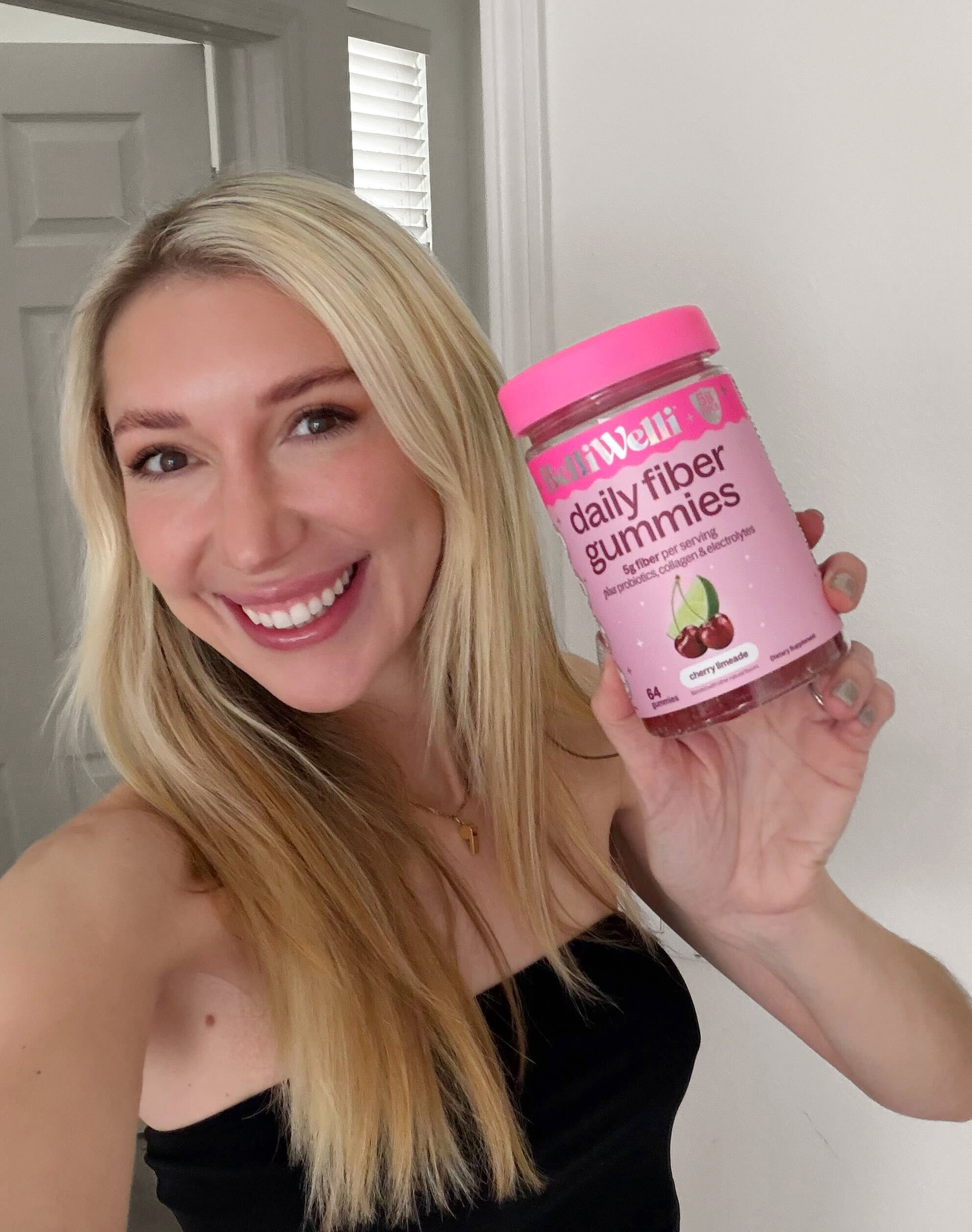 Woman smiling and holding Cherry Limeade and Watermelon BelliWelli fiber gummy jars
