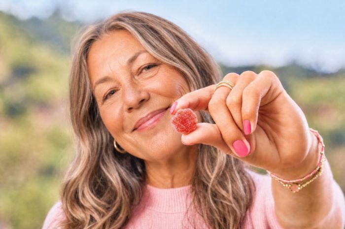 Woman smiling and holding up a gummy