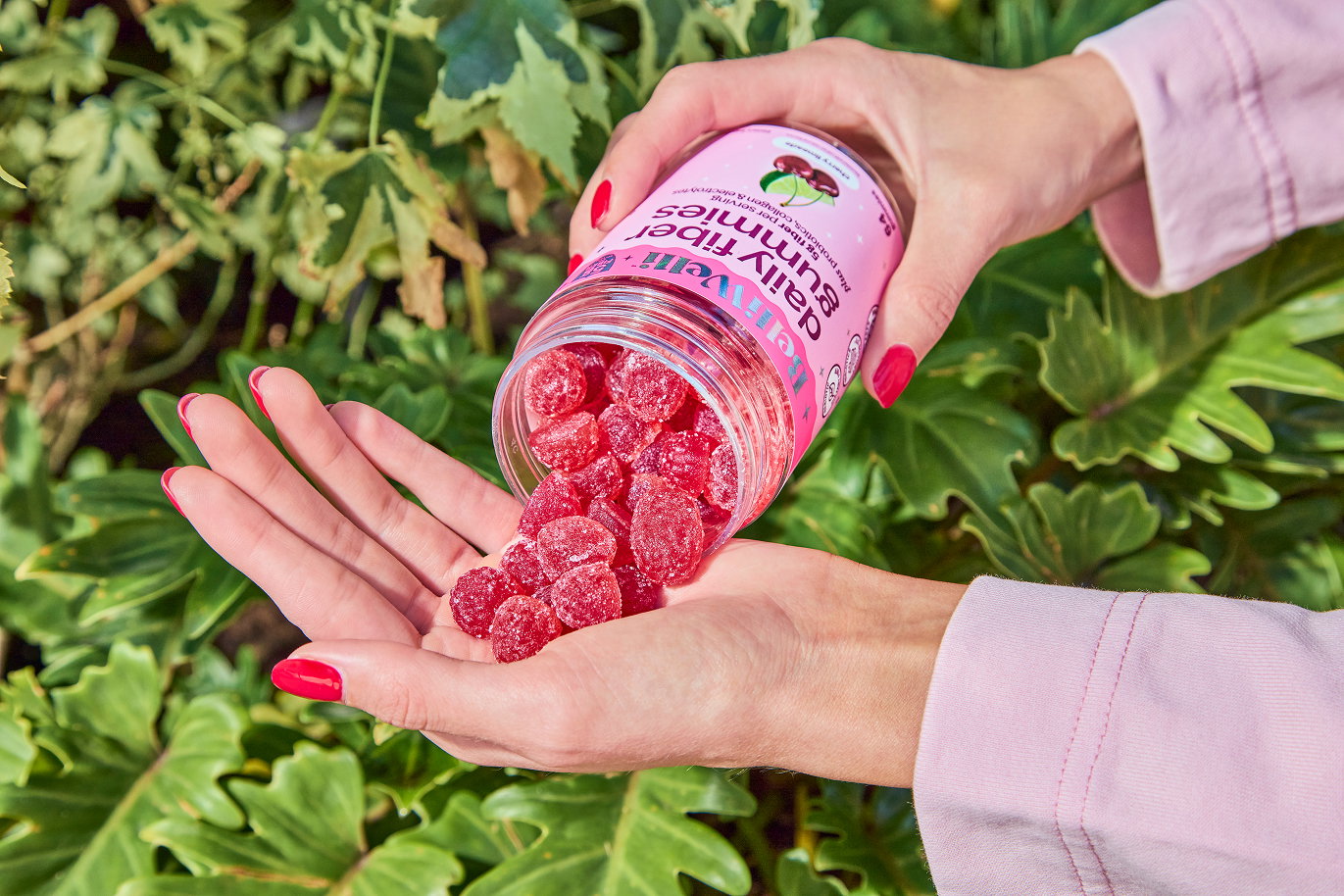 Hand pouring BelliWelli Cherry Limeade fiber gummies from the jar into an open palm