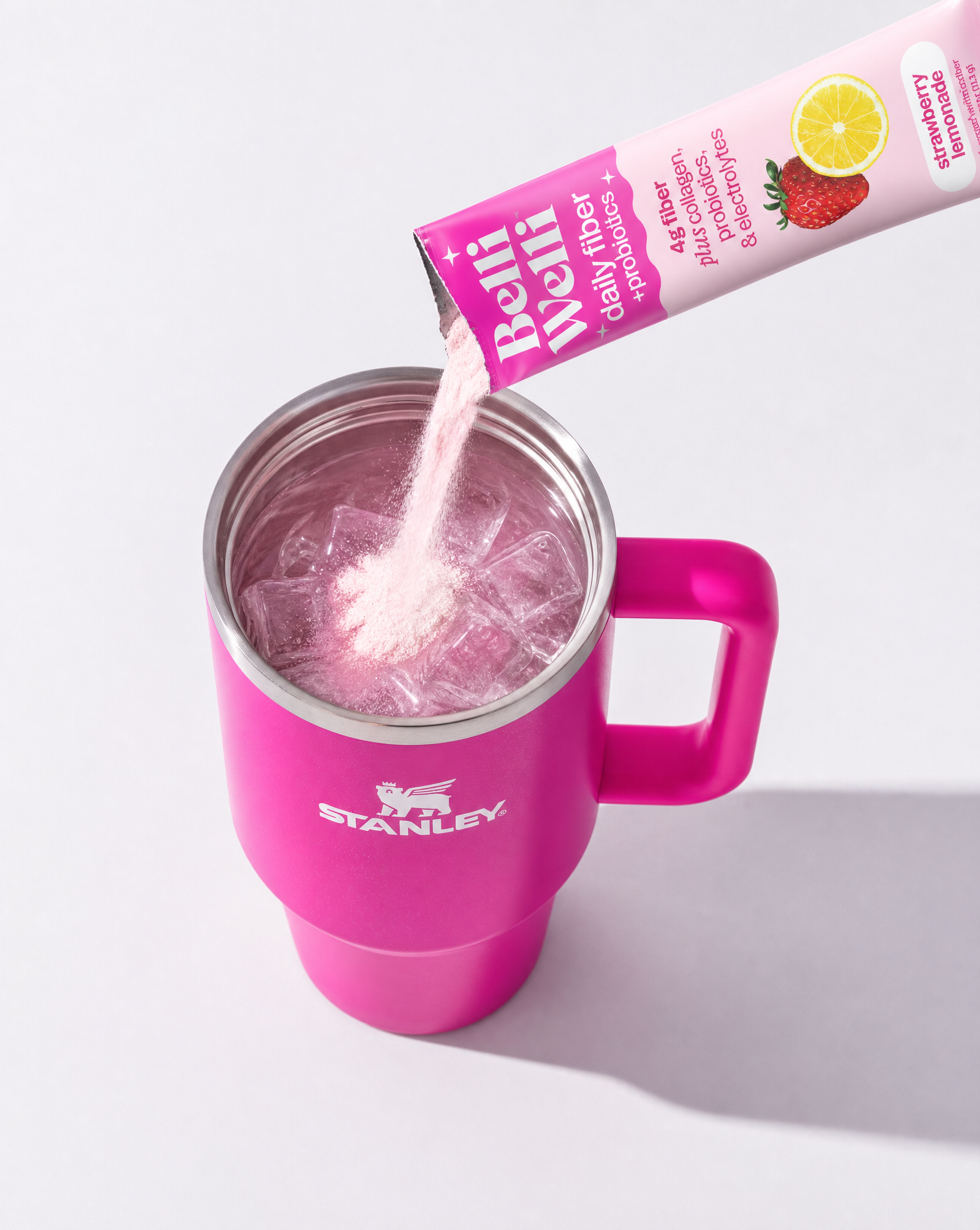 BelliWelli Strawberry Lemonade stick pack being poured into a pink tumbler of ice water