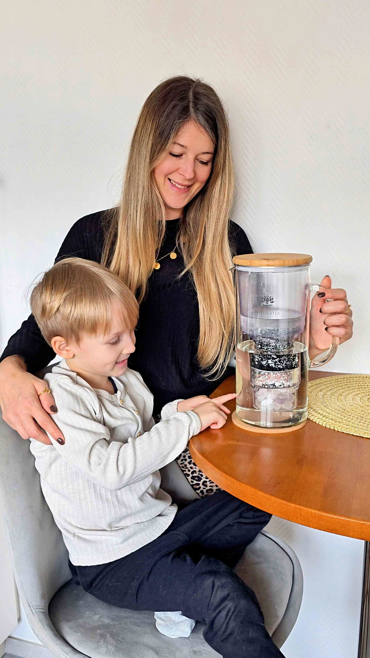 Mutter und Kind trinken Wasser aus der Filterkanne Enya