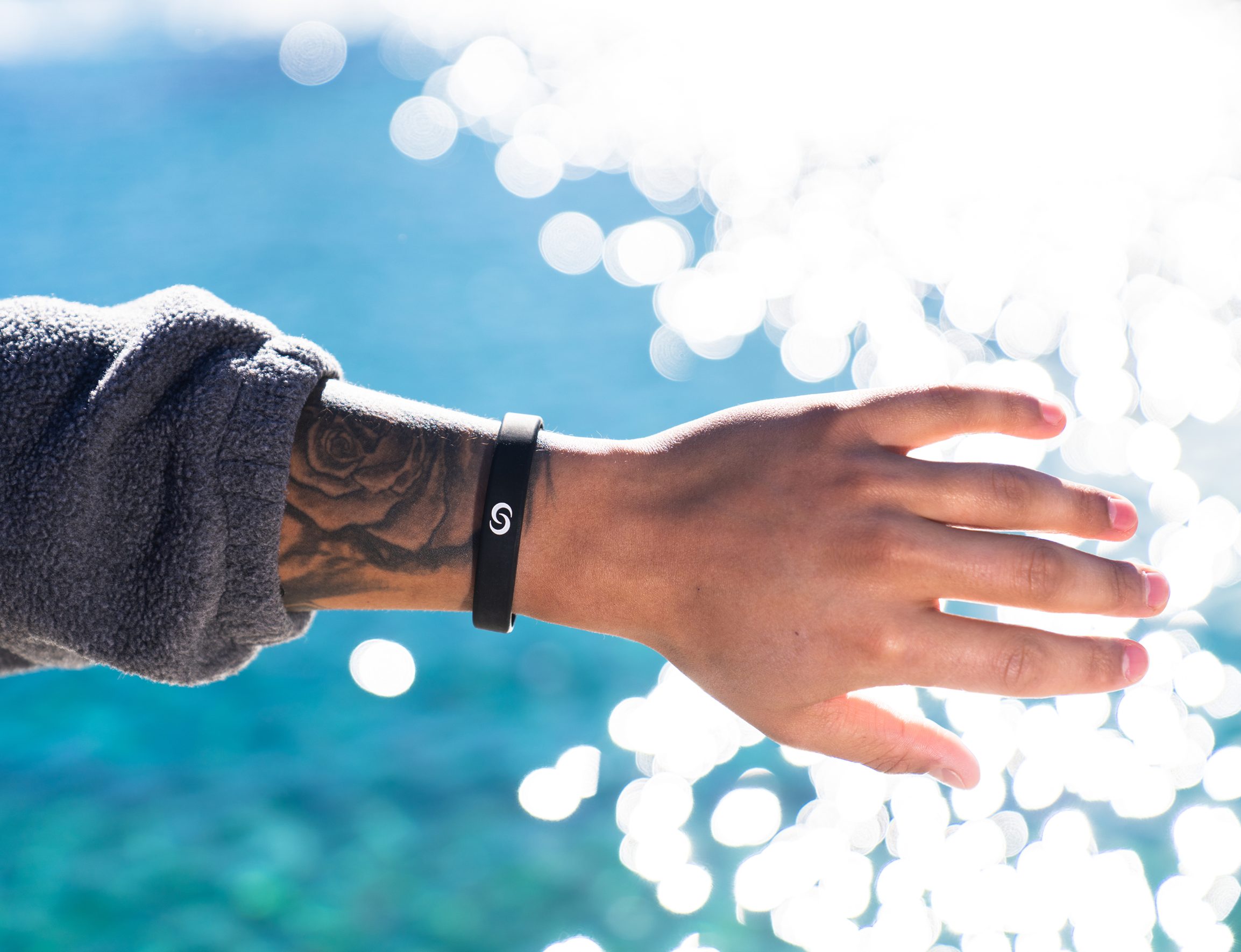 Black Smart Silicone Band worn on a wrist over sparkling water