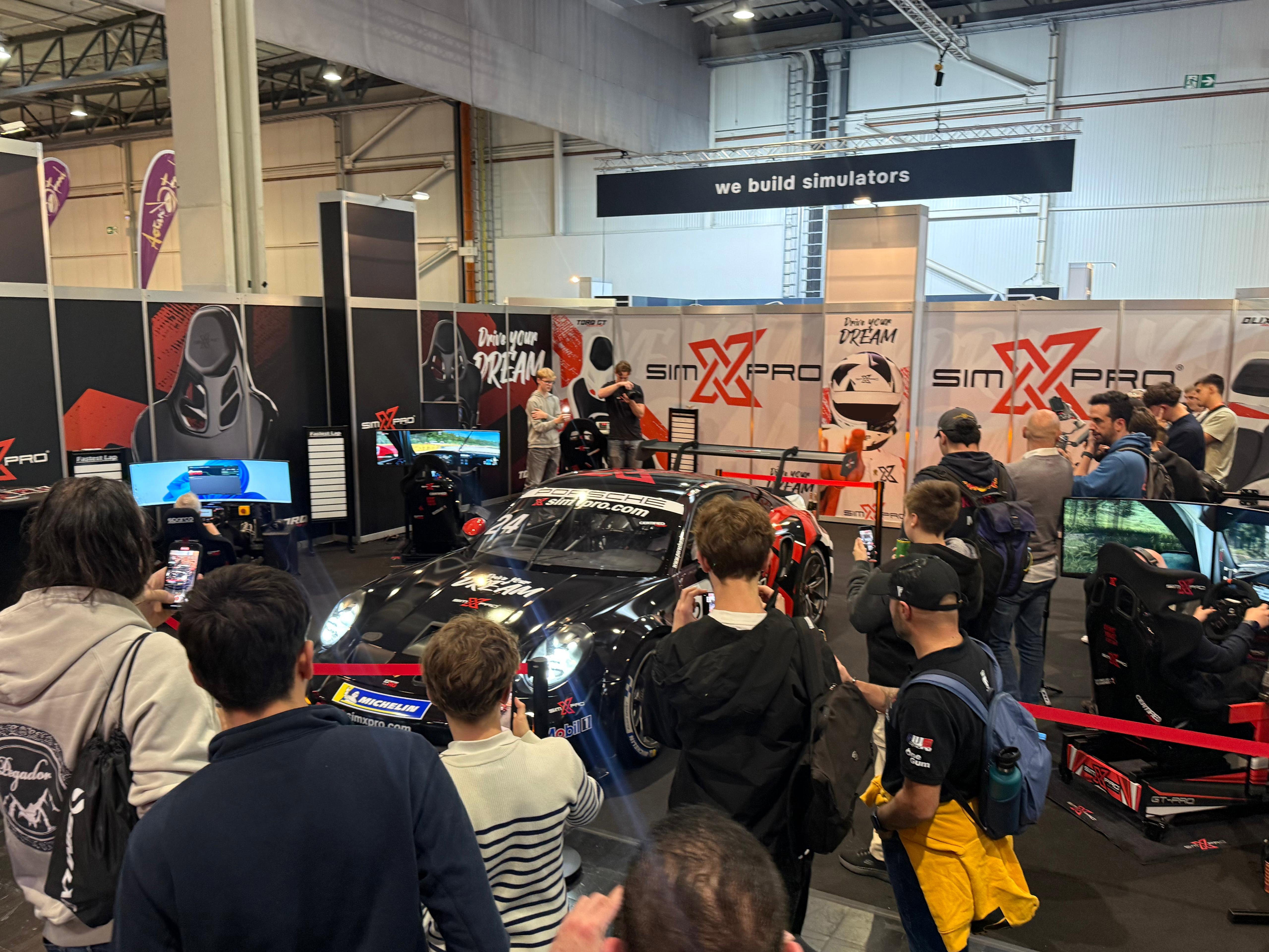 Crowd of visitors at the SimXPro stand with the SimXPro Porsche race car and GT-PRO cockpits