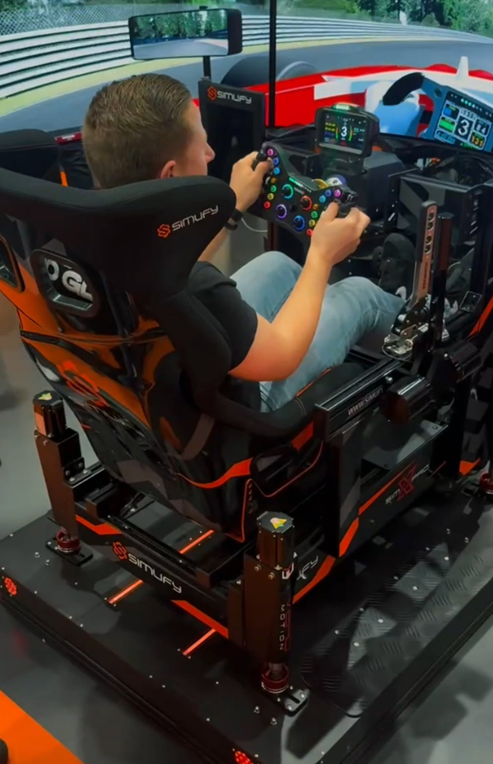 Visitor driving a SimXPro GT-PRO with a Simufy seat on a full 6DOF motion platform at the Simufy booth