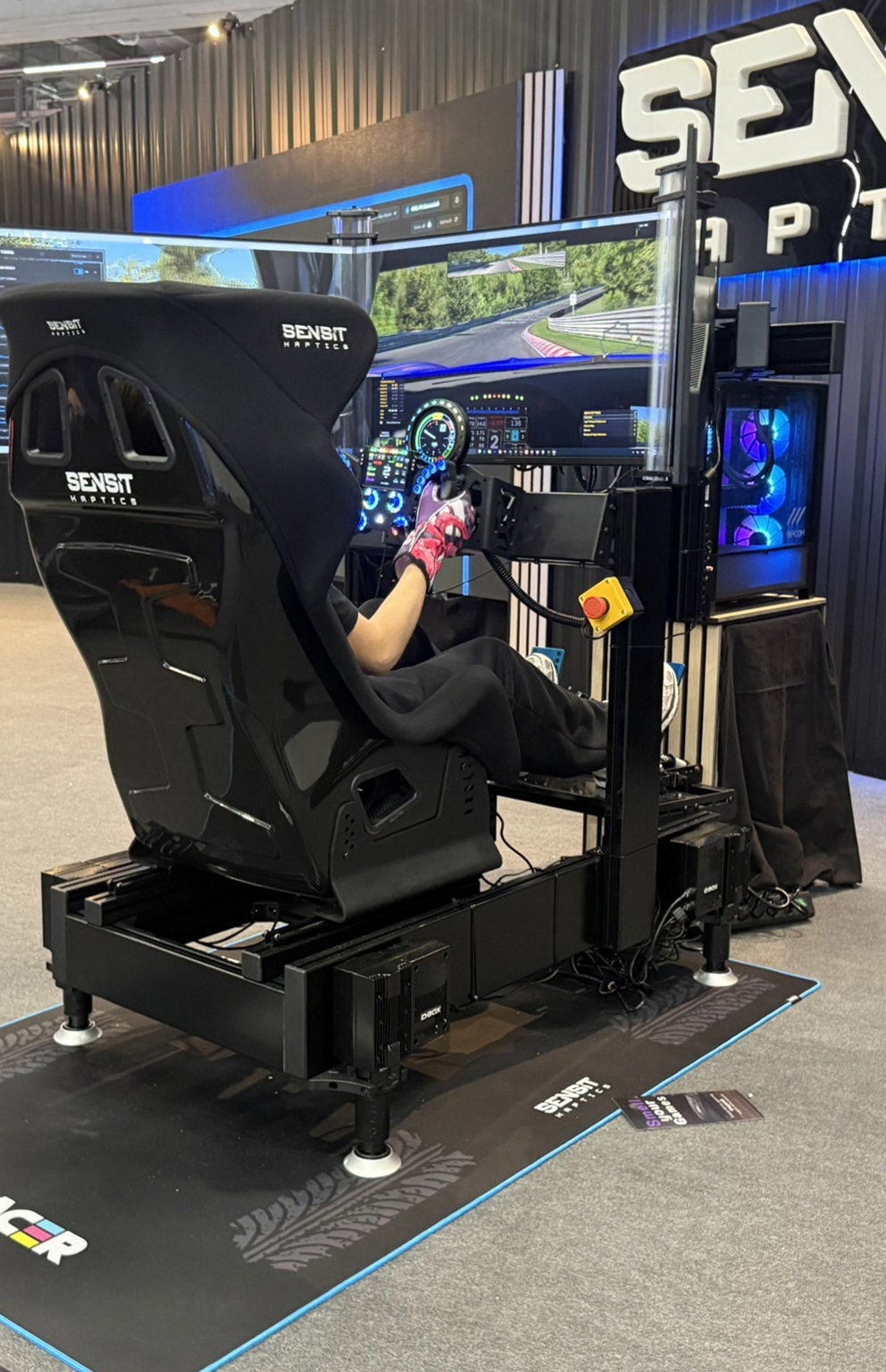 Black SimXPro GT-PRO with D-BOX motion actuators and a Sensit haptic seat at the Sensit booth