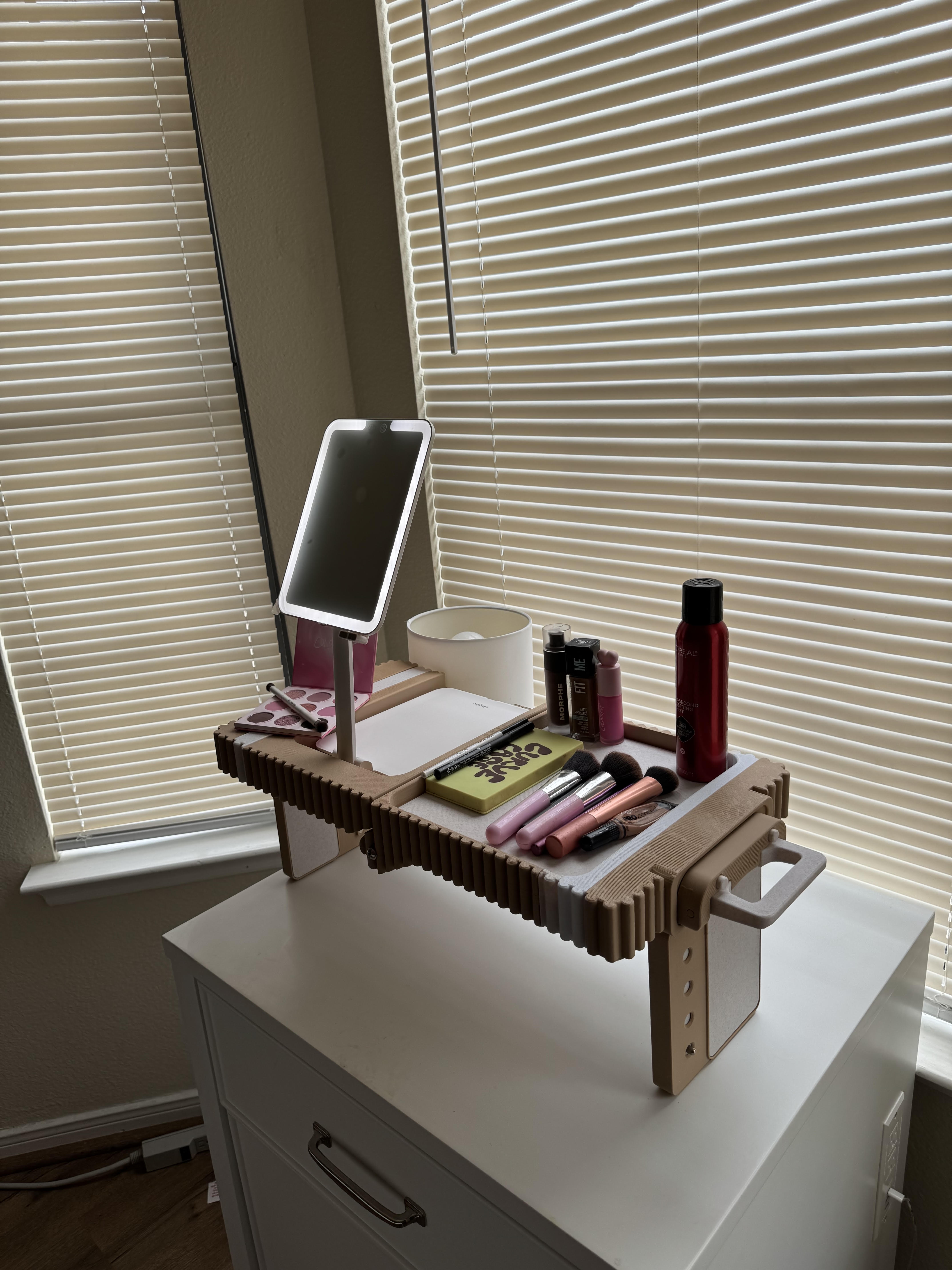 Lap Vanity set up on a dresser by a sunlit window, lighted mirror raised and brushes, lipsticks and hairspray in the tray