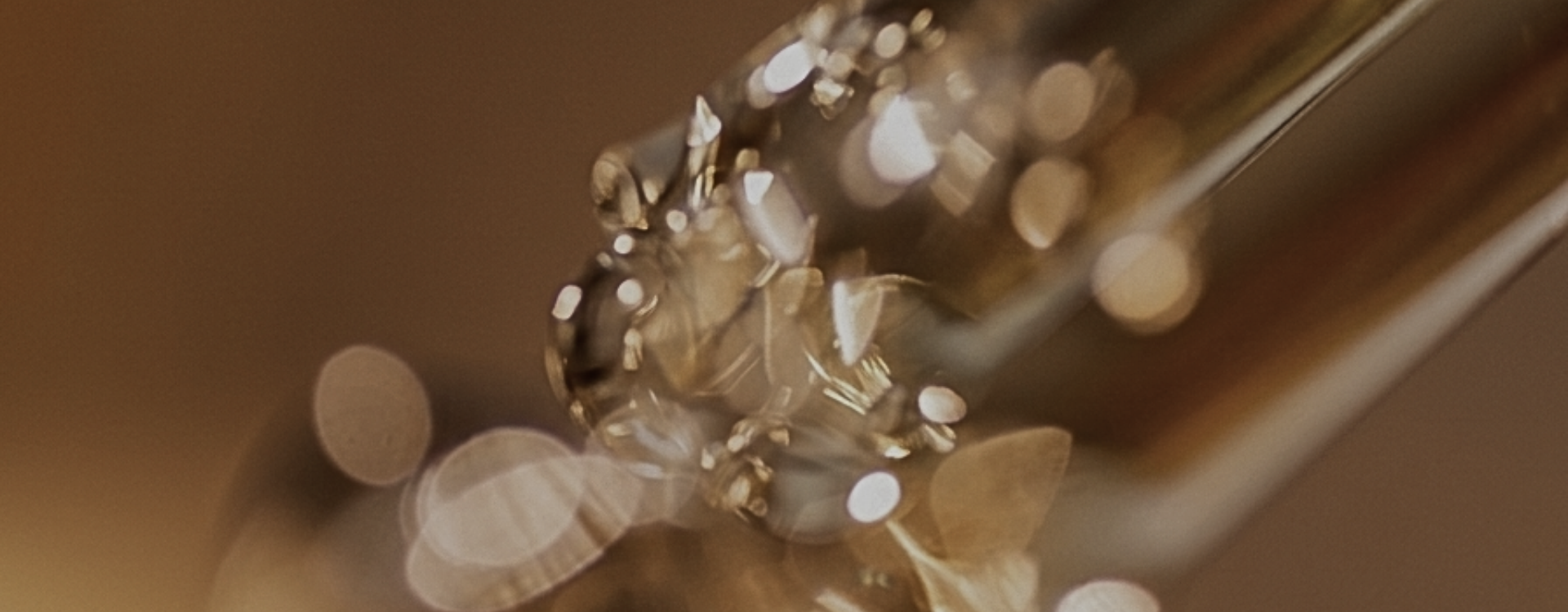 Close-up of an extrait de parfum bottle with floating gold flakes