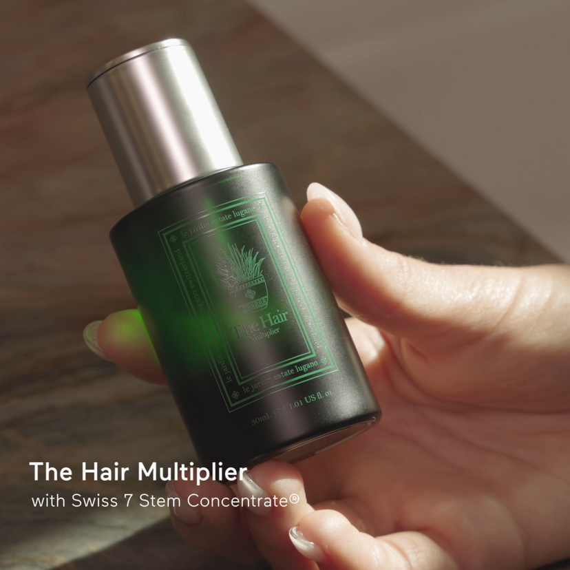 The Hair Multiplier held in a hand, showing the serum applied at the scalp