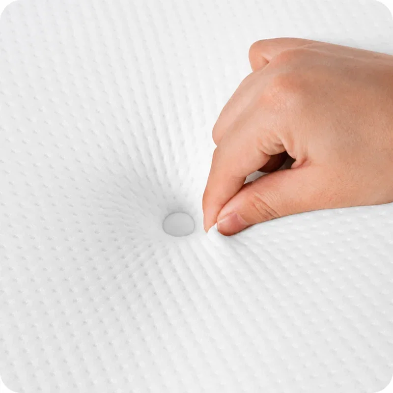 Hand pressing beside the snap button in the center of the white pillow cover