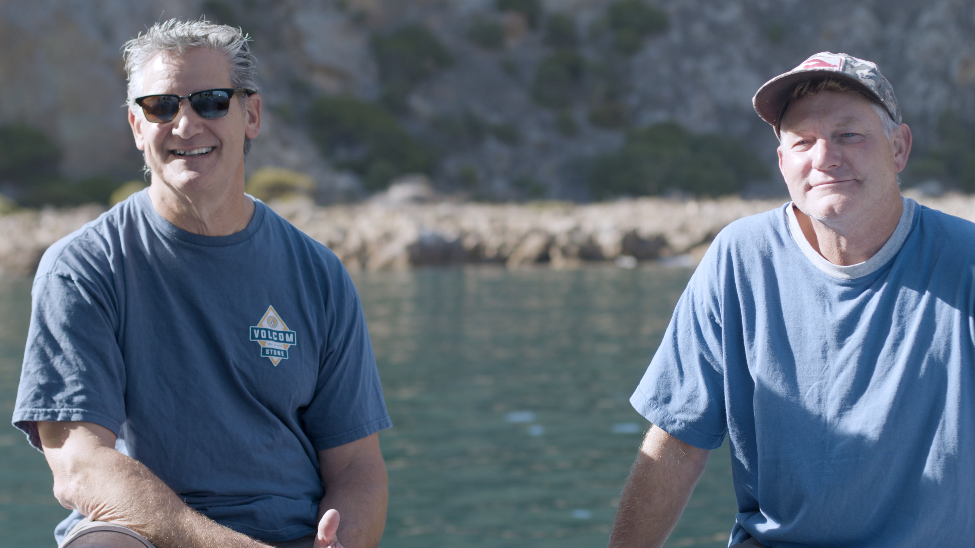Gear Keeper's two founders, both lifelong divers, smiling on a boat in a sunlit cove