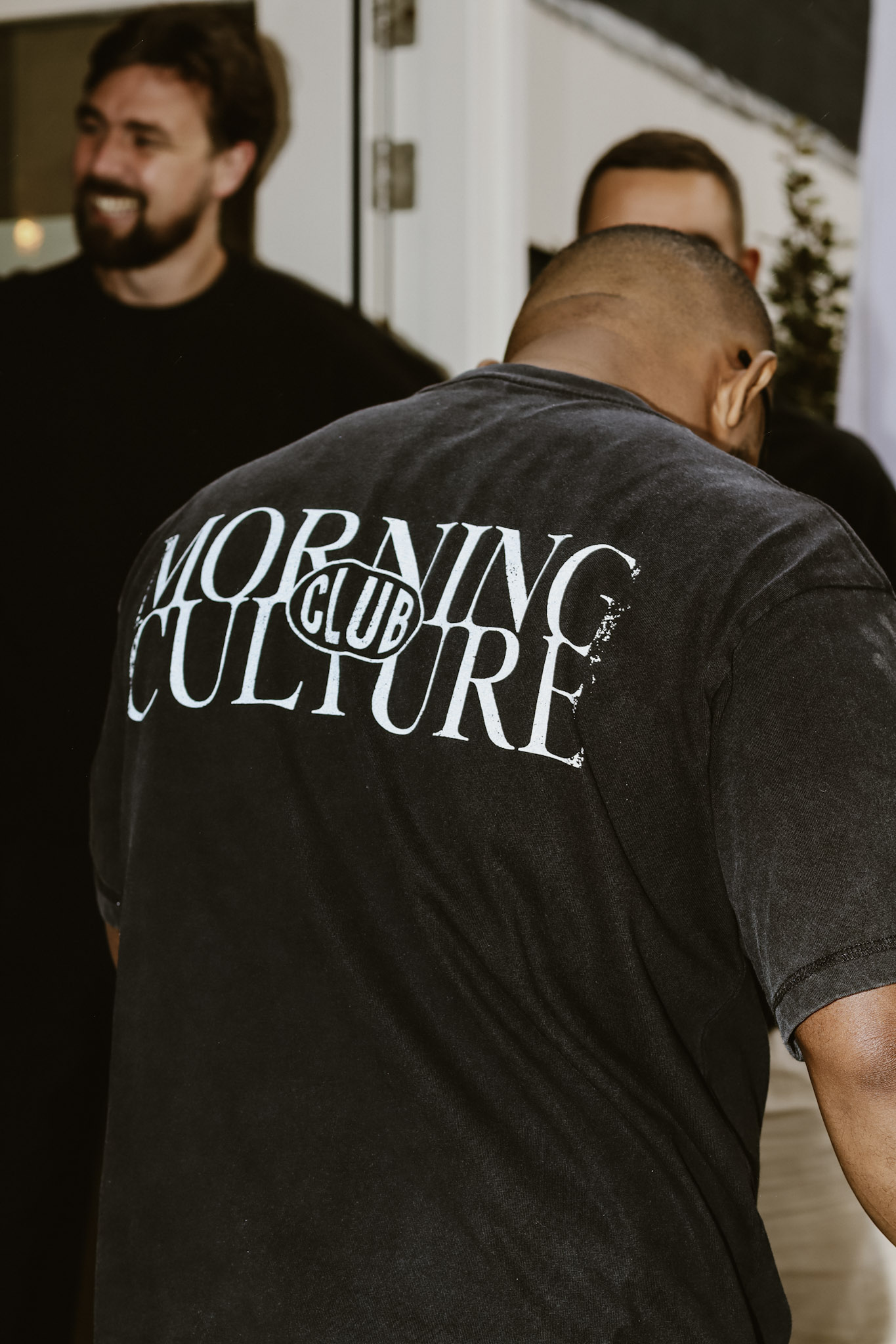Person in a black oversized hoodie on an early morning street with coffee