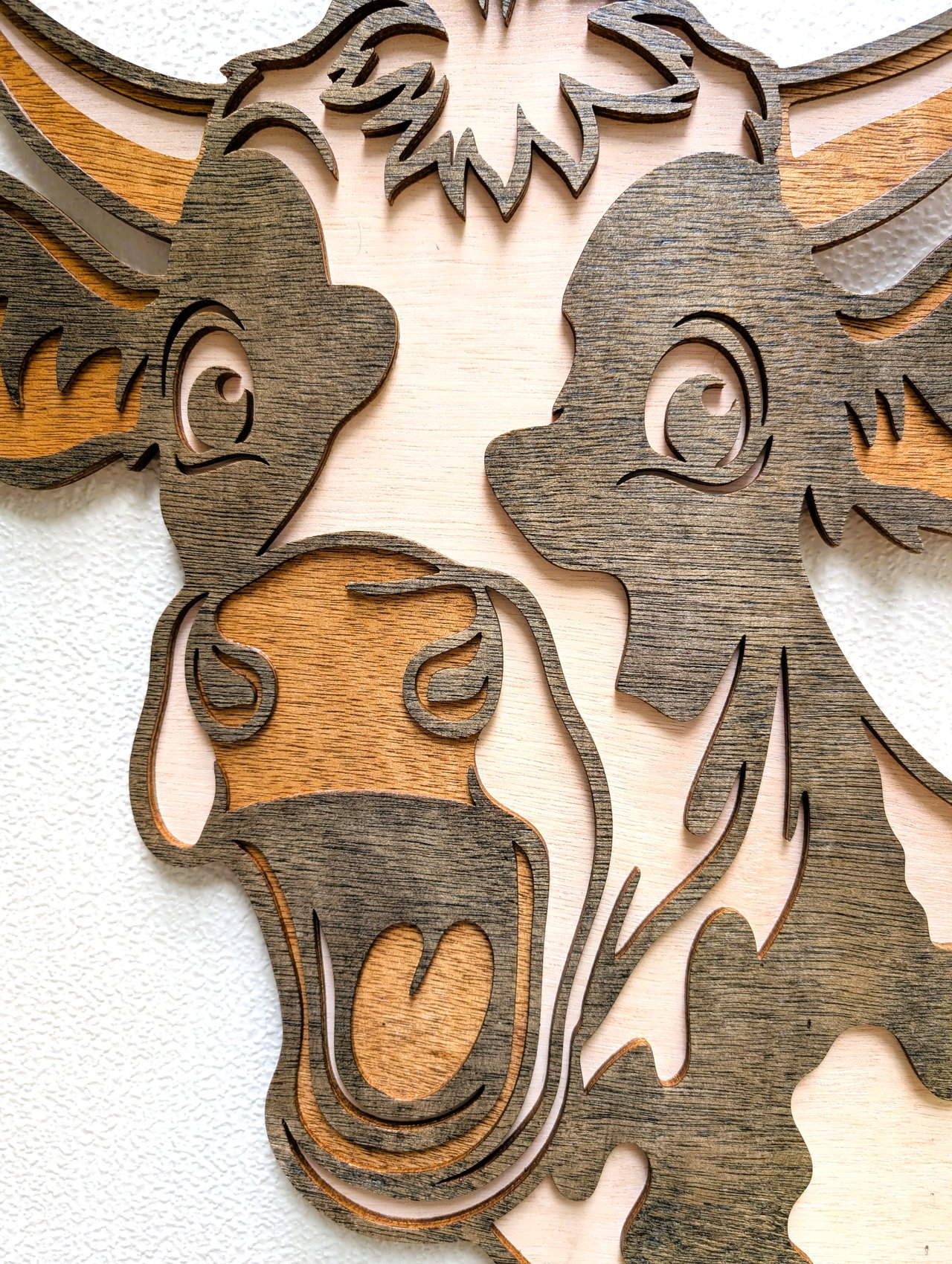 Close-up of wooden artwork depicting a cartoonish cow's face with detailed carving