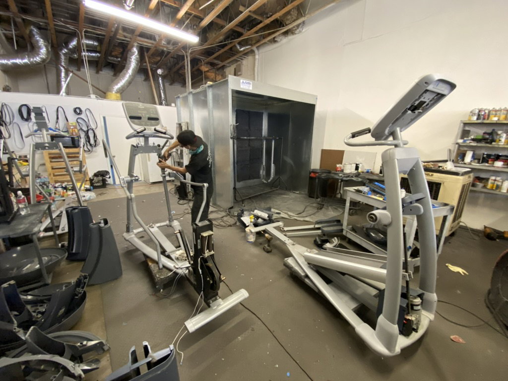 Ace Fitness technician rebuilding stripped-down Precor ellipticals in the Riverside refurbishing workshop