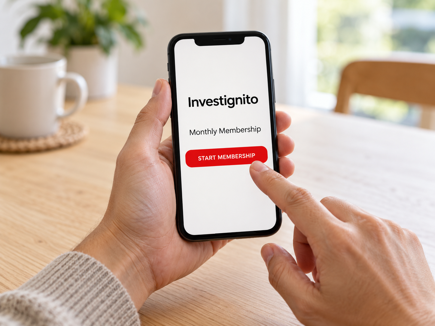 Hand holding a phone showing the Investignito Monthly Membership screen with a Start Membership button
