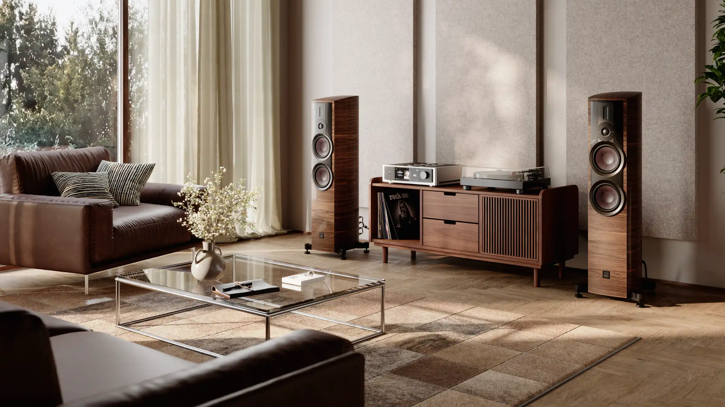 Bright two-channel listening room with a pair of walnut tower speakers flanking a walnut console with an integrated amplifier, a turntable and vinyl records