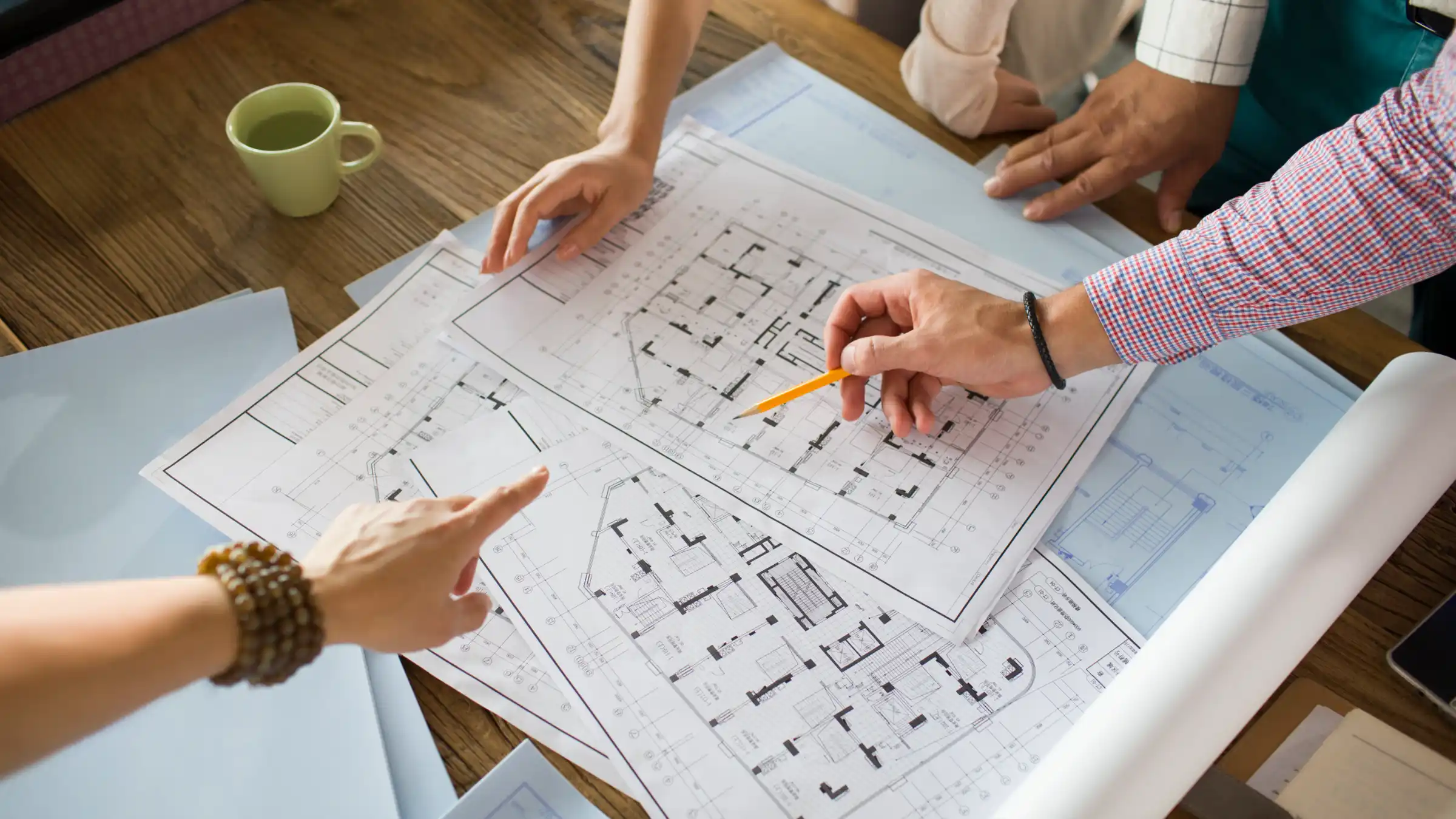 Audiolab team members reviewing system floor plans together on a wooden table, one pointing with a pencil to plan a maintenance visit
