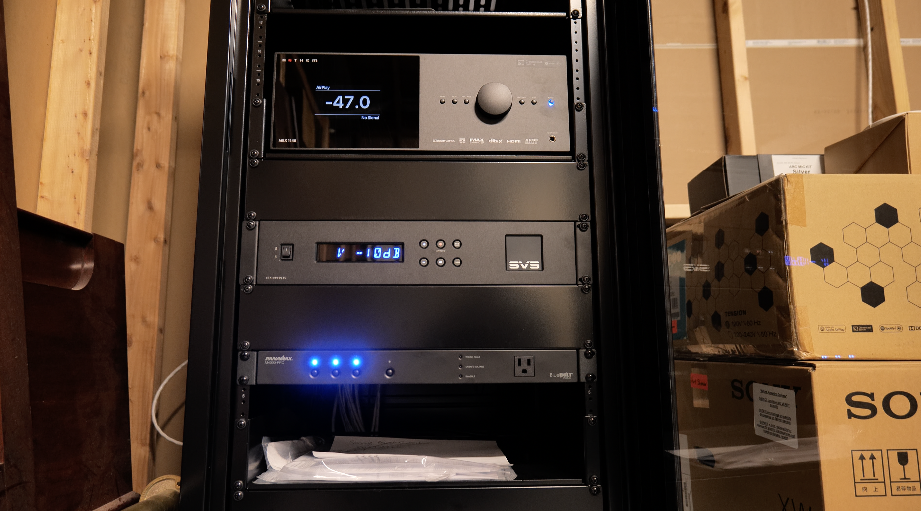 Black equipment rack with an Anthem AV processor, SVS amplifier and Panamax power conditioner, displays glowing