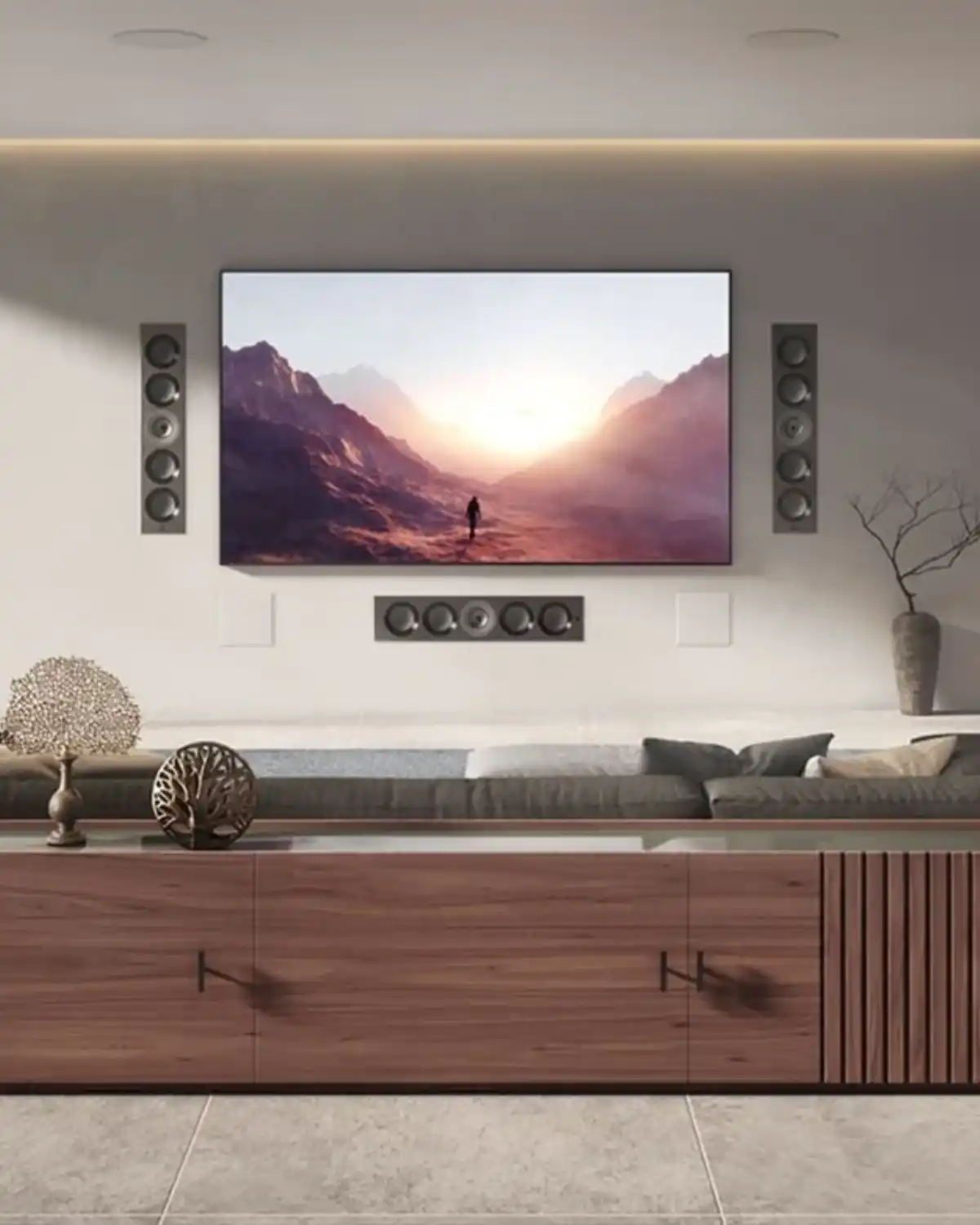 KEF in-wall speakers flanking a wall-mounted TV, with an in-wall center speaker below and in-ceiling speakers above, in a living room with a walnut media cabinet