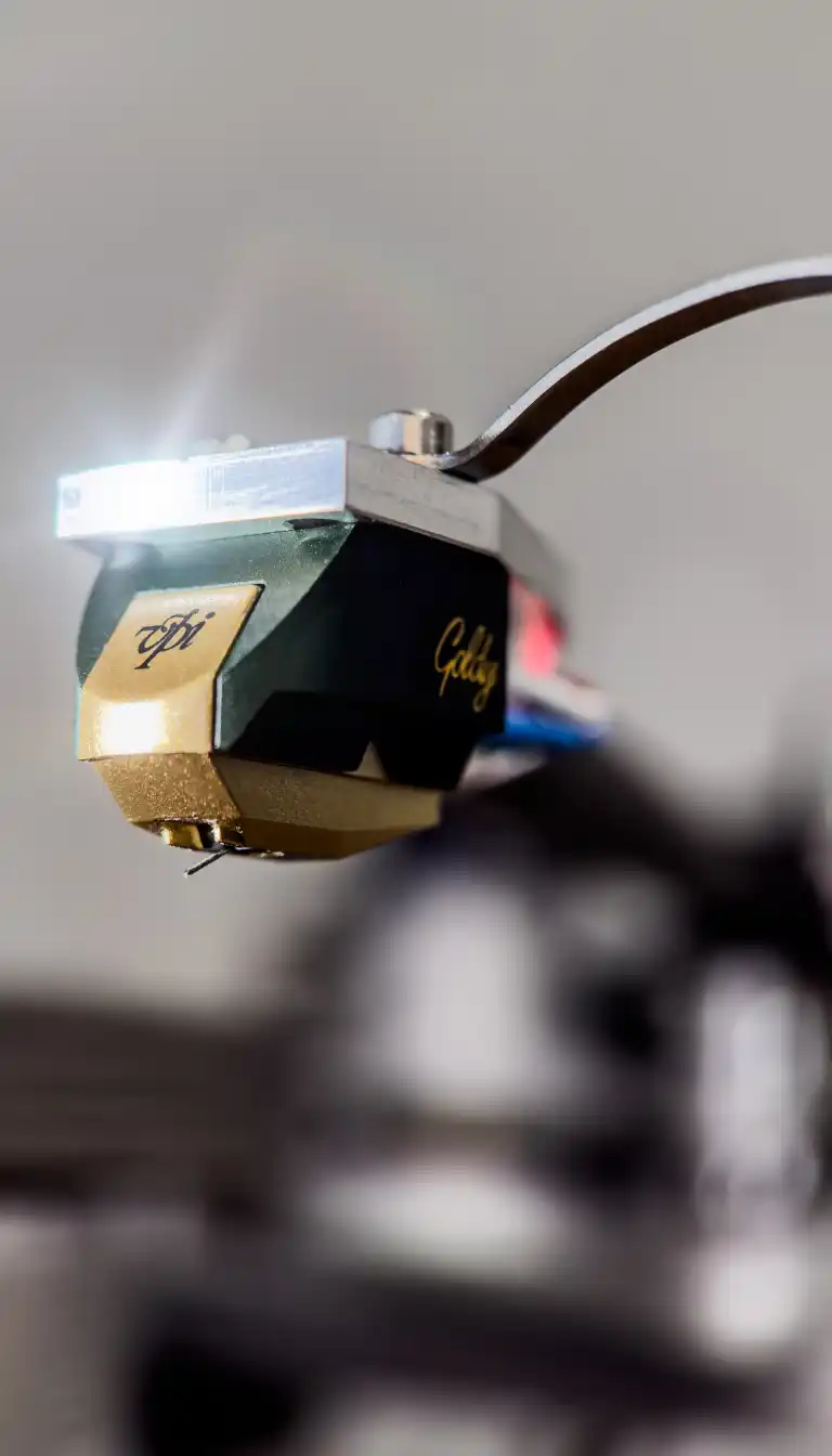 Close-up of a green and gold VPI phono cartridge mounted on a tonearm, its stylus catching the light