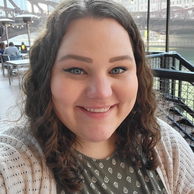 Customer photo of Emma smiling at the camera on a riverside terrace.