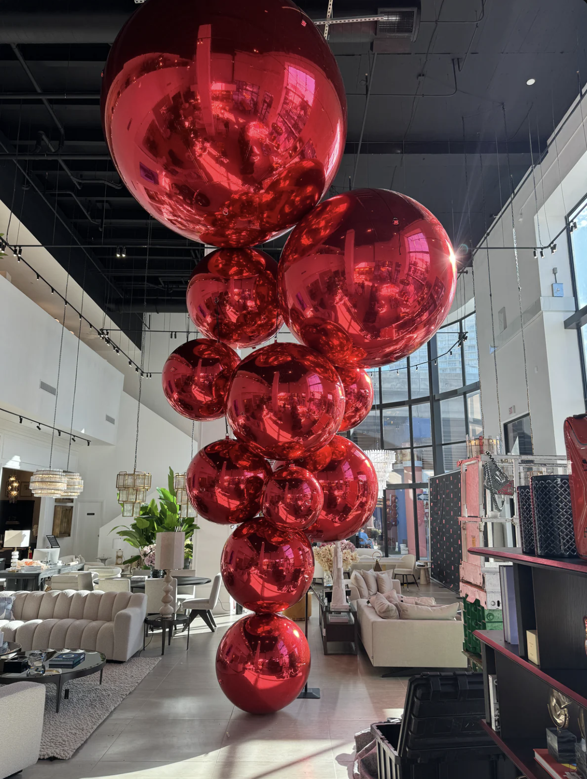 Cascading cluster of giant red chrome balls hanging in a bright furniture showroom