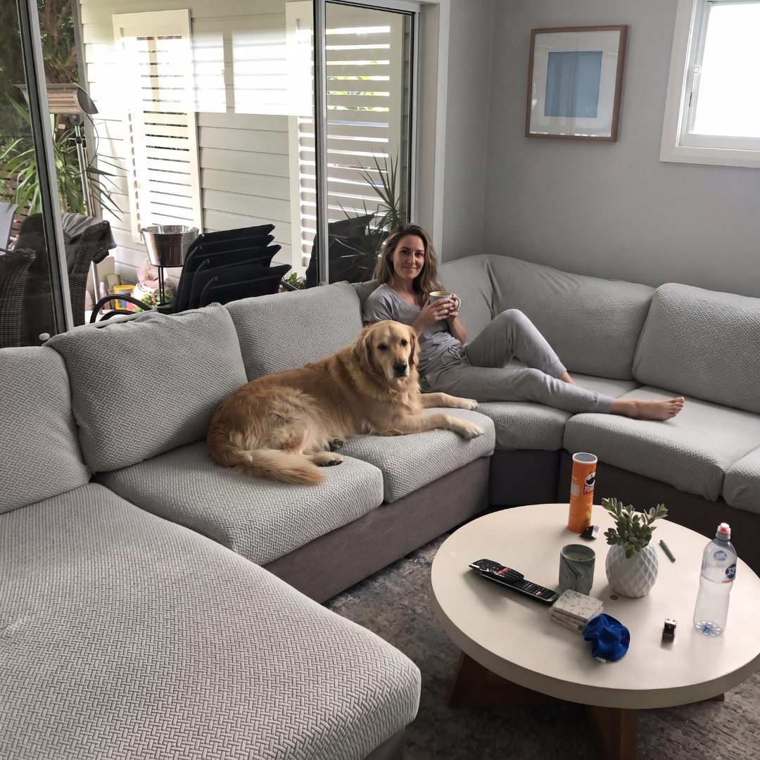 Woman relaxing on a sectional with CouchCoats Classic covers, her golden retriever lying beside her