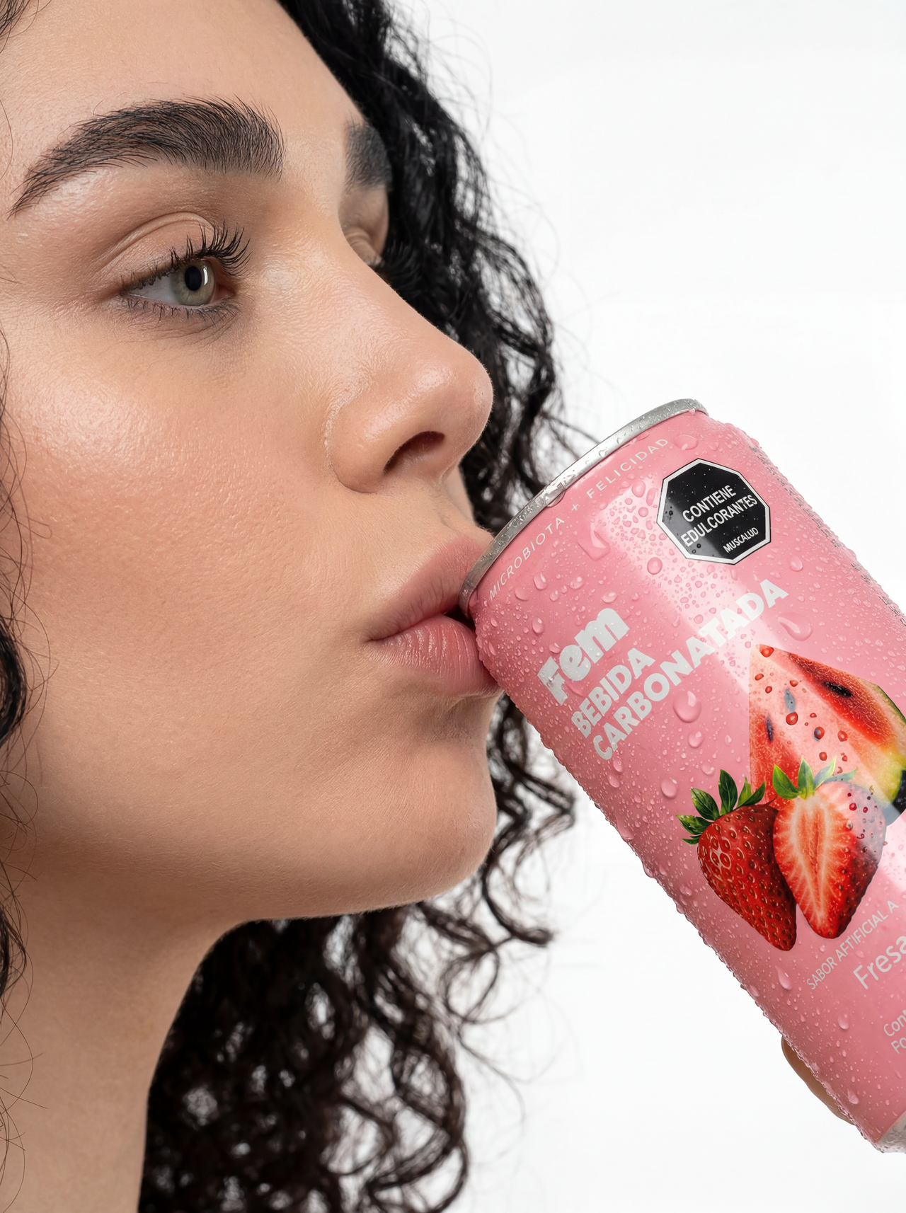 Close-up of a woman with curly hair drinking a pink strawberry-flavored carbonated drink can