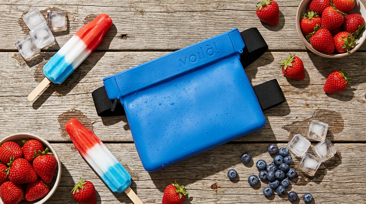 Blue waterproof fanny pack on wooden surface surrounded by strawberries, blueberries, ice cubes, and red-white-blue popsicles