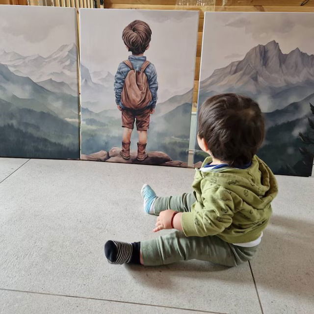 Toddler sitting in front of a set of three mountain adventure prints