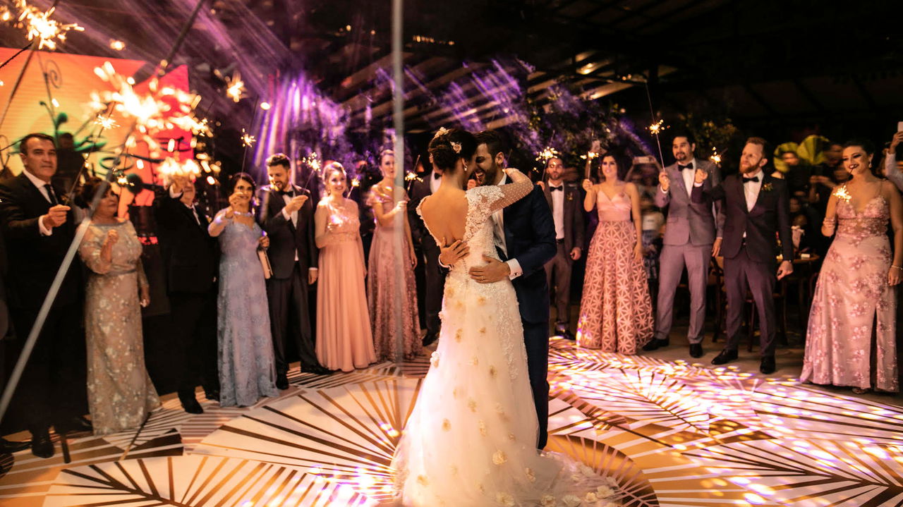 Bride and groom sharing their first dance while wedding guests hold sparklers on the dance floor