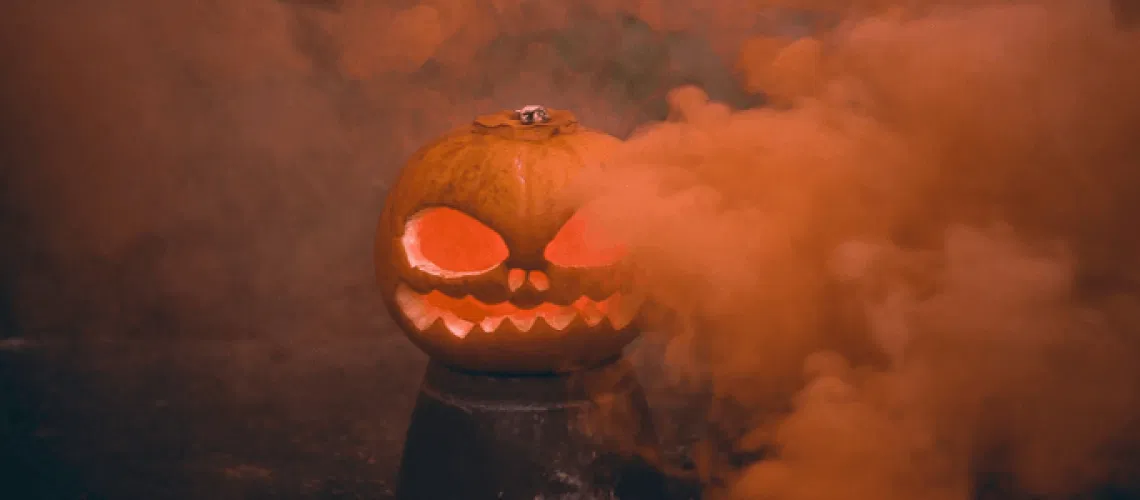 Carved jack-o-lantern pumpkin glowing with orange smoke from a Halloween smoke bomb