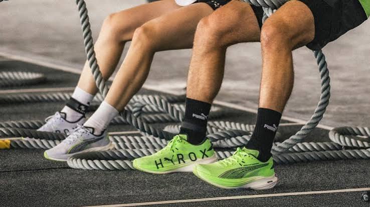 Athletes wearing Puma Hyrox trainers sitting among battle ropes on a gym floor