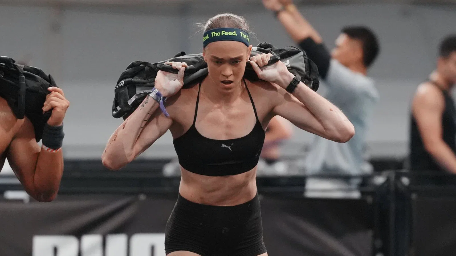 Hyrox athlete carrying a sandbag on her shoulders during the sandbag lunges station