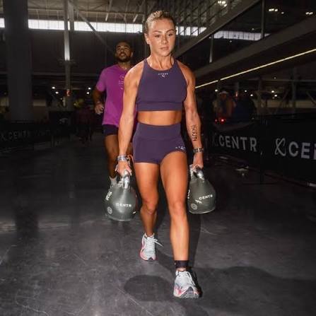 Female Hyrox athlete carrying two kettlebells during the farmers carry station