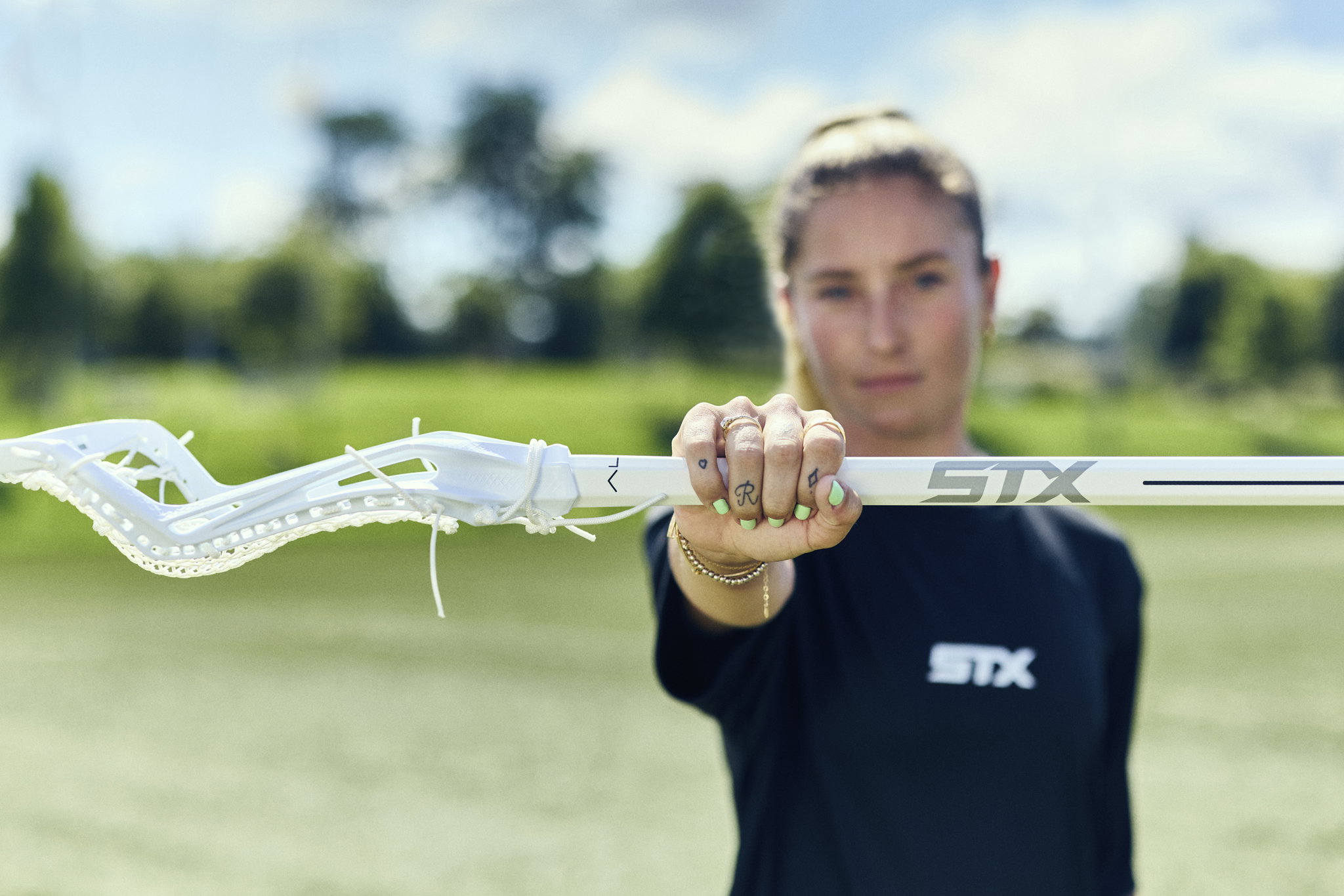 Team USA's Ally Kennedy holding a white Aline Complete stick straight out toward the camera on a sunny field