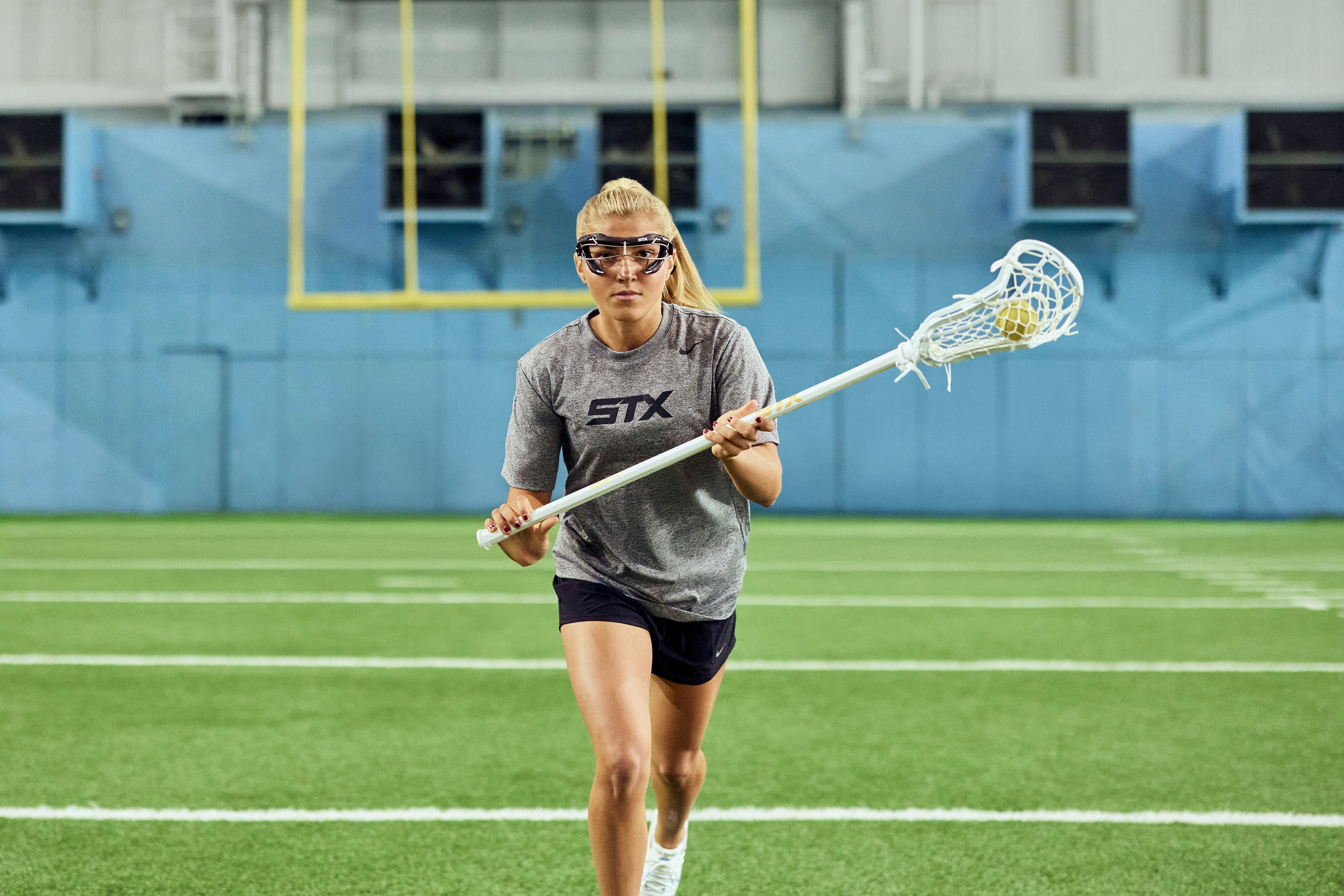 Chloe Humphrey running at the camera with her white Crux Pro stick