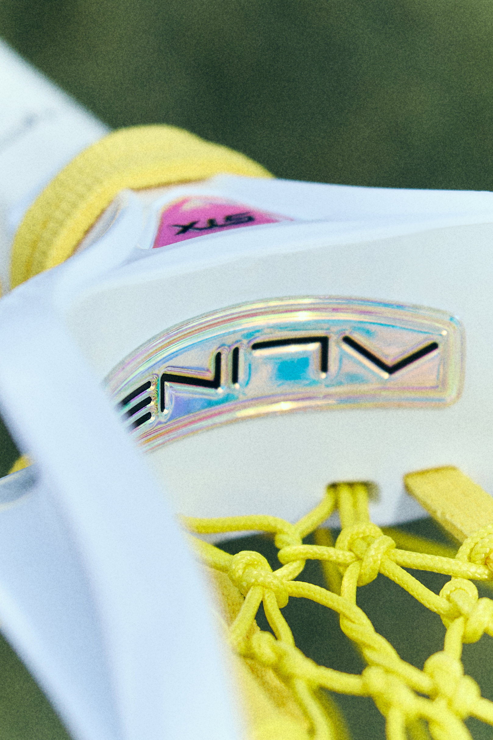 Close-up of the Aline head in white with its iridescent Aline badge, pink STX logo and yellow pocket