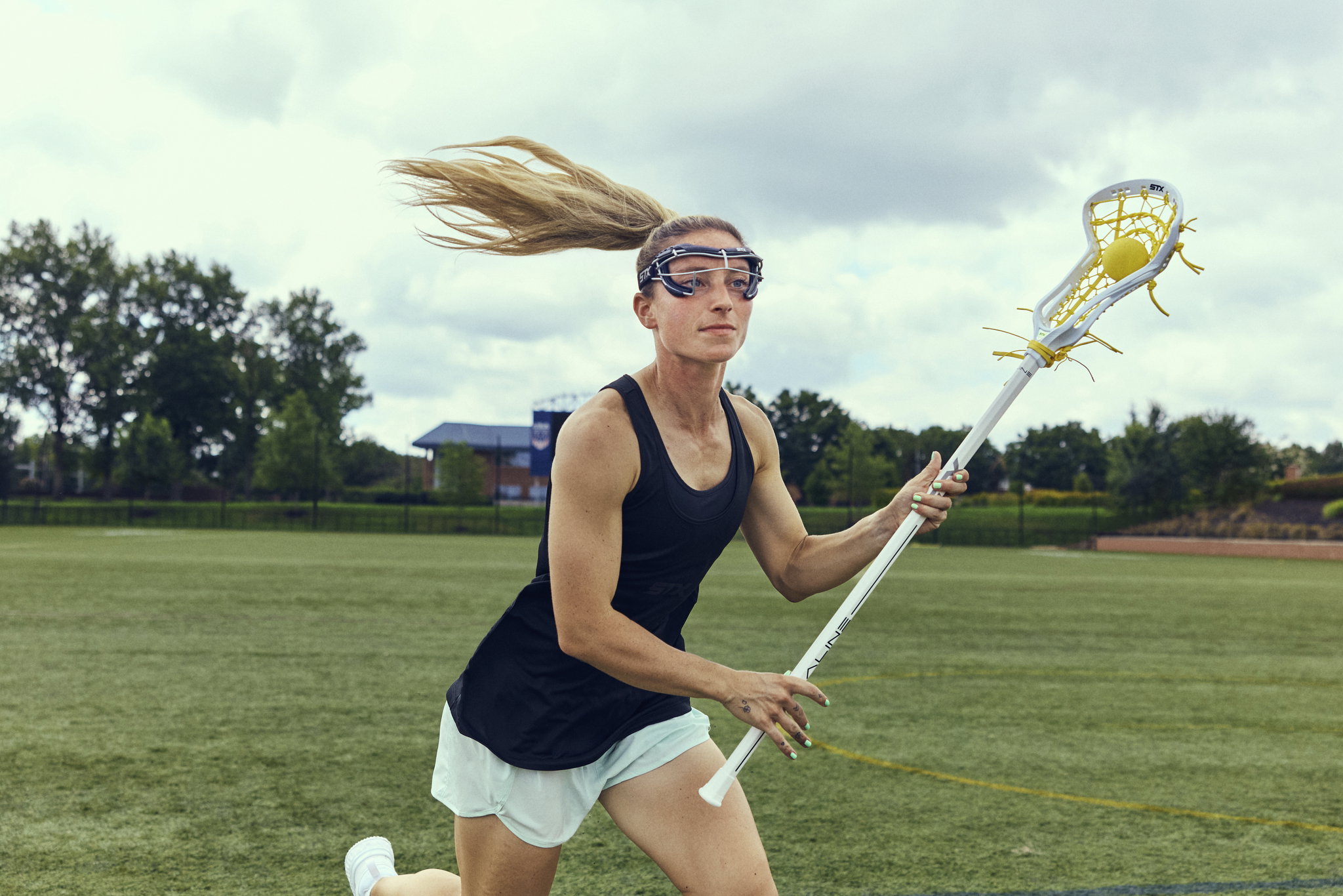 Team USA's Ally Kennedy sprinting across the field in transition, carrying a white Aline stick with a yellow pocket and ball