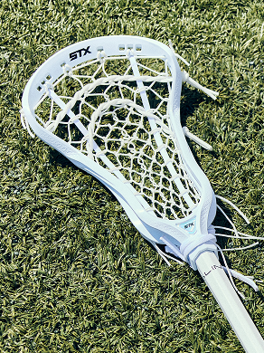 White Aline Complete stick head with a white mesh pocket lying on turf
