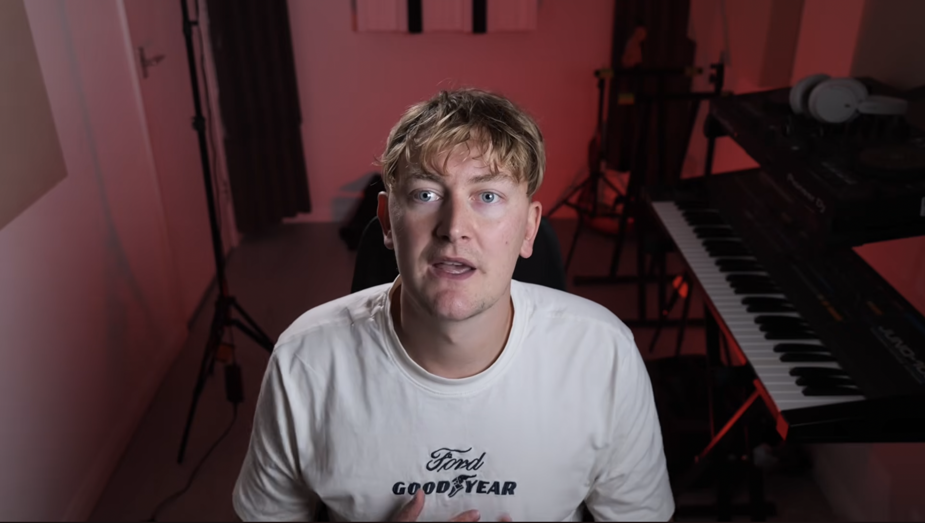 Producer working on a track in a dark home studio lit in violet and green