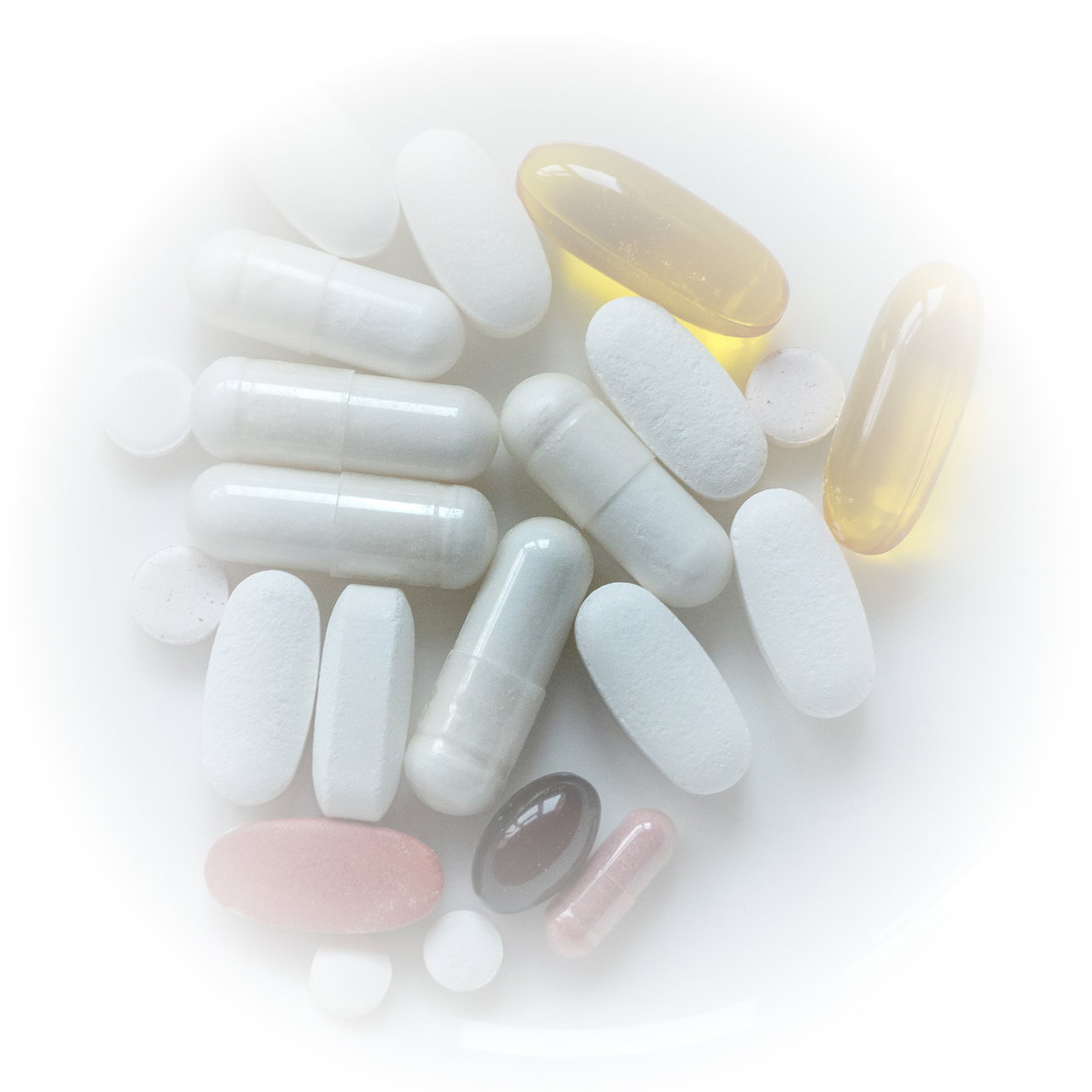 Close-up of assorted white, yellow, pink, and brown pills and capsules.