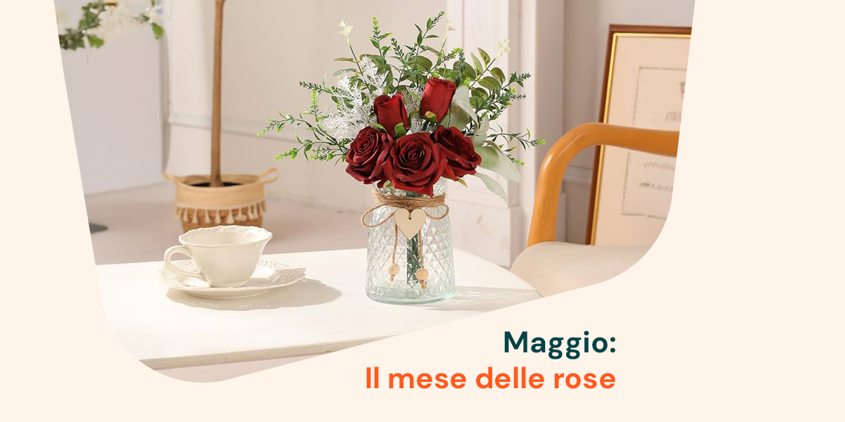Composizione floreale con rose rosse in un vaso decorato, su tavolino con tazza da tè: un’elegante ispirazione per celebrare maggio, il mese delle rose.