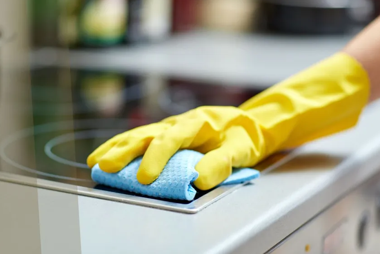Pulizia del piano cottura con guanti e panno: un gesto semplice per mantenere la cucina igienica e funzionale nella stagione calda.