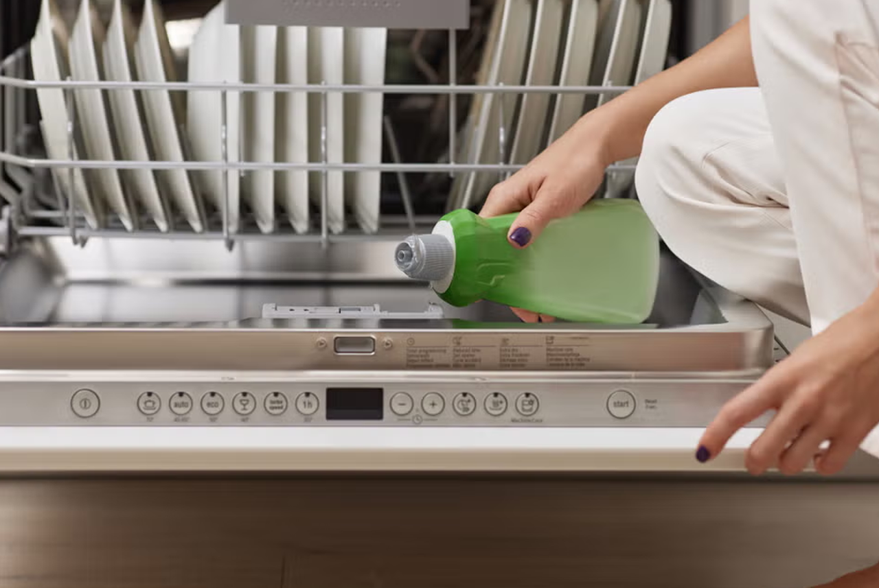 Mano che versa il detersivo liquido nella lavastoviglie aperta: un errore frequente se dosato male, secondo Mamma Avilia, che spiega come usarlo in modo corretto per un lavaggio efficace.
