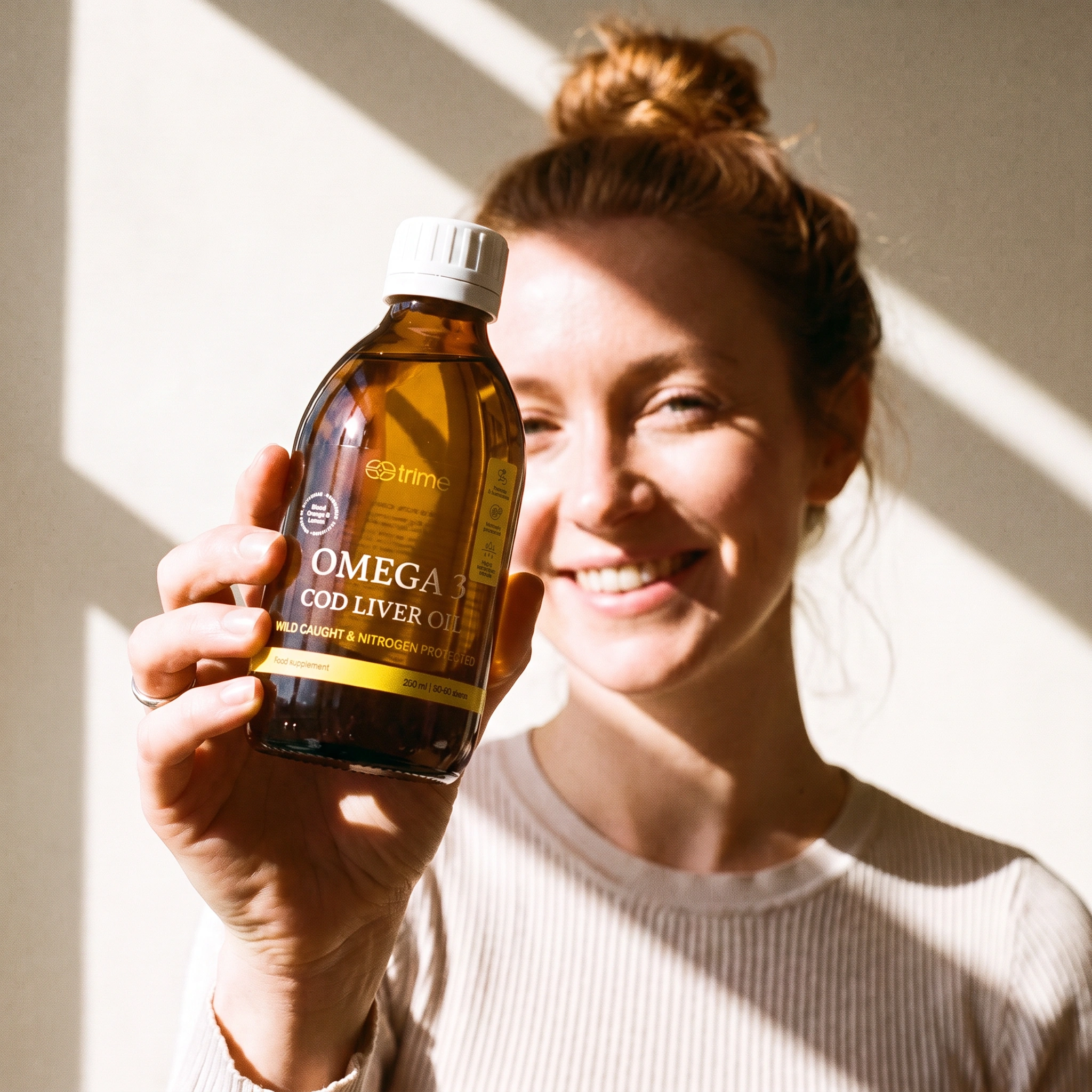 Woman pouring a teaspoon of Trime cod liver oil at her kitchen counter in the morning