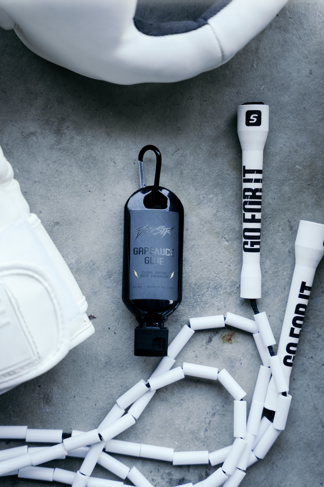 GRPSAUCE Glue bottle with its carabiner next to a jump rope and boxing gloves